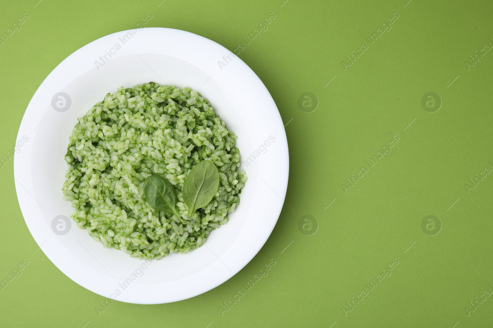 Photo of Delicious spinach risotto on light green background, top view. Space for text