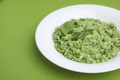 Photo of Delicious spinach risotto on light green background, closeup