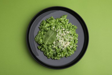 Photo of Delicious spinach risotto with parmesan cheese on light green background, top view