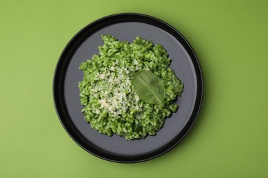 Photo of Delicious spinach risotto with parmesan cheese on light green background, top view