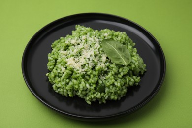 Photo of Delicious spinach risotto with parmesan cheese on light green background