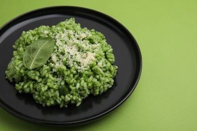 Photo of Delicious spinach risotto with parmesan cheese on light green background, closeup