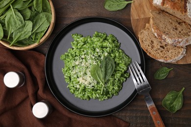 Photo of Delicious spinach risotto with parmesan cheese served on wooden table, flat lay. Space for text