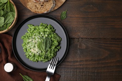 Photo of Delicious spinach risotto with parmesan cheese served on wooden table, flat lay. Space for text