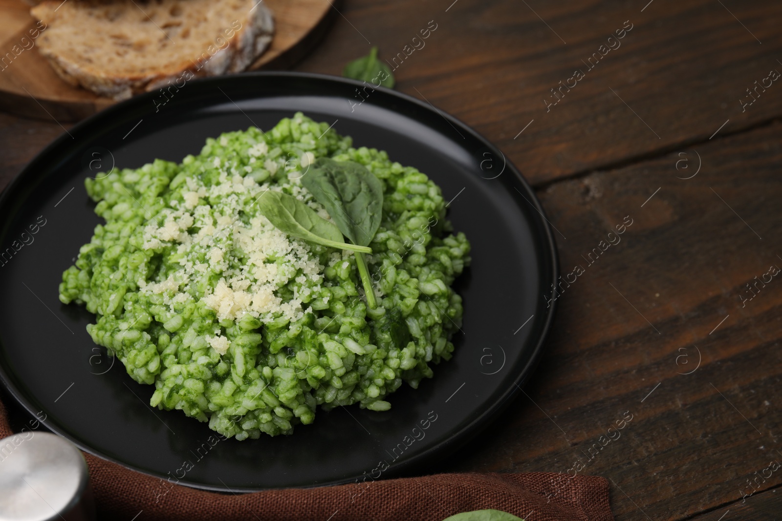 Photo of Delicious spinach risotto with parmesan cheese on wooden table, closeup. Space for text