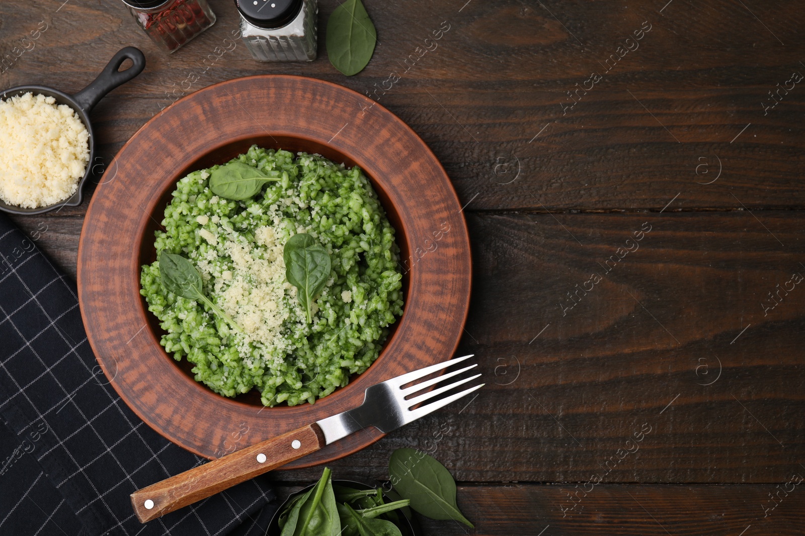 Photo of Delicious spinach risotto with parmesan cheese served on wooden table, flat lay