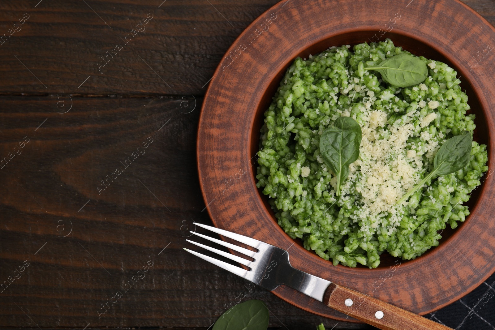 Photo of Delicious spinach risotto with parmesan cheese served on wooden table, flat lay. Space for text