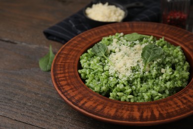 Photo of Delicious spinach risotto with parmesan cheese on wooden table, closeup. Space for text