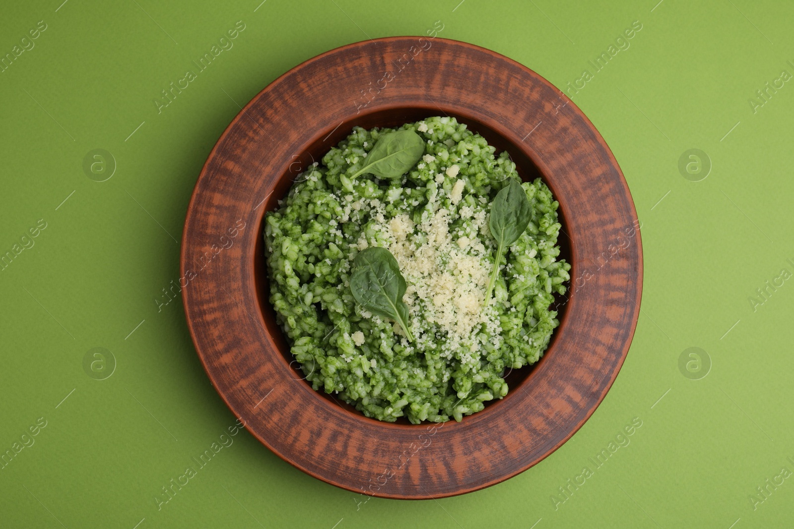 Photo of Delicious spinach risotto with parmesan cheese on light green background