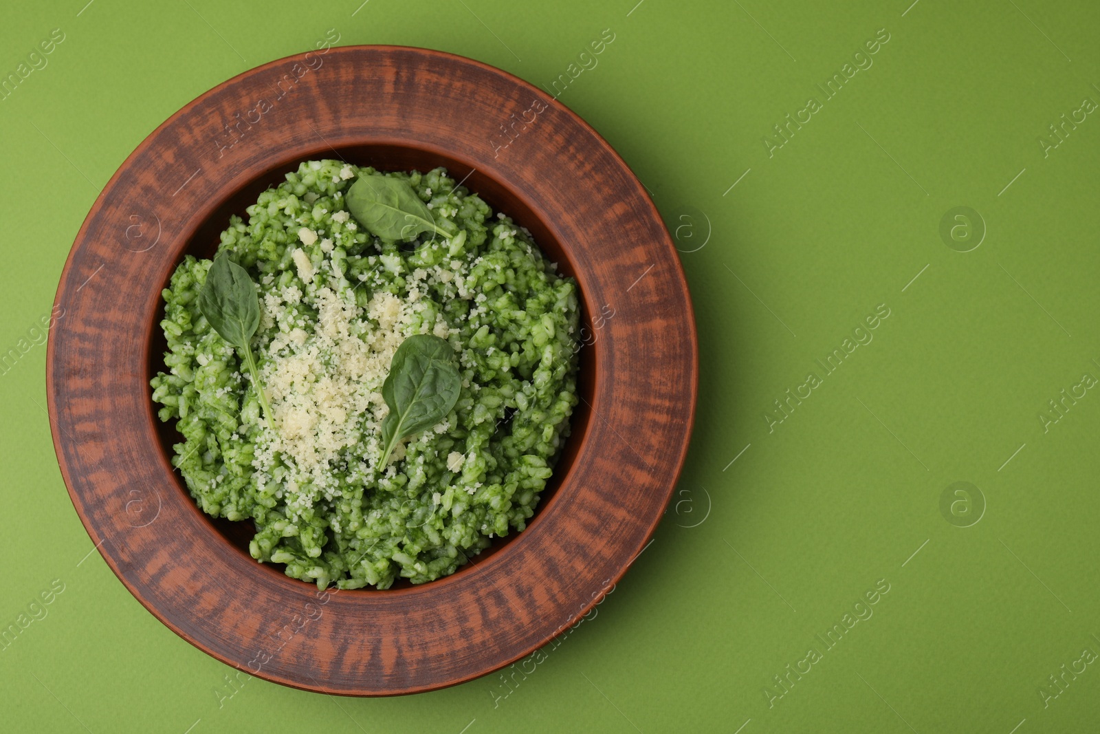 Photo of Delicious spinach risotto with parmesan cheese on light green background