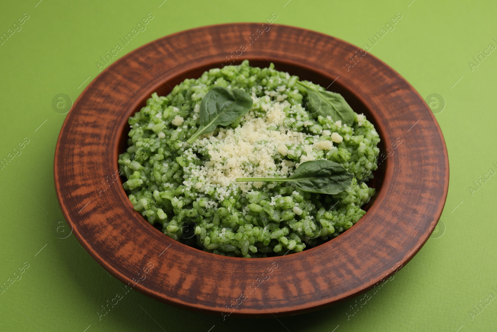 Photo of Delicious spinach risotto with parmesan cheese on light green background