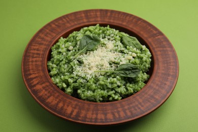 Photo of Delicious spinach risotto with parmesan cheese on light green background