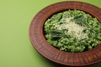 Photo of Delicious spinach risotto with parmesan cheese on light green background