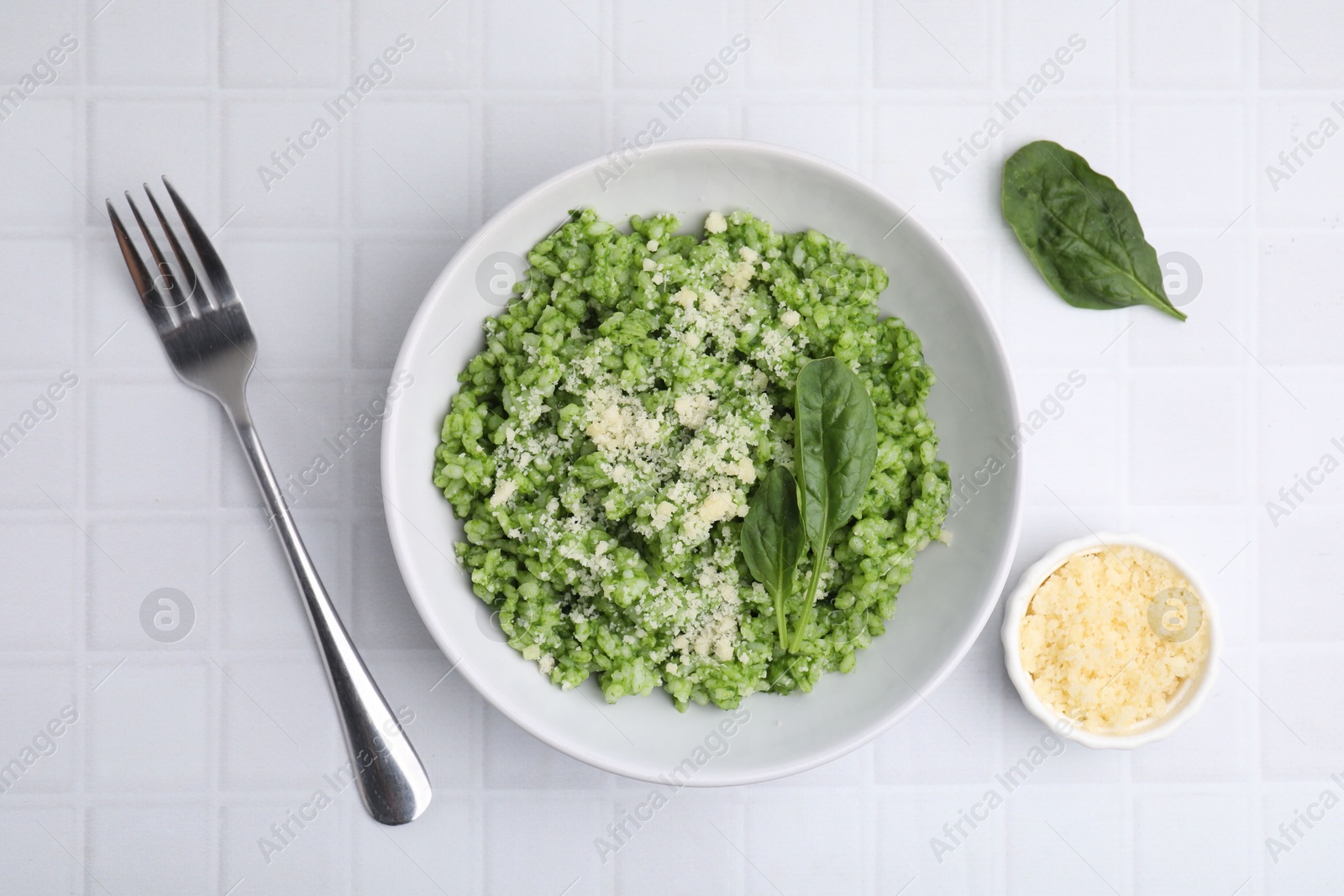 Photo of Delicious spinach risotto with parmesan cheese served on white tiled table, flat lay