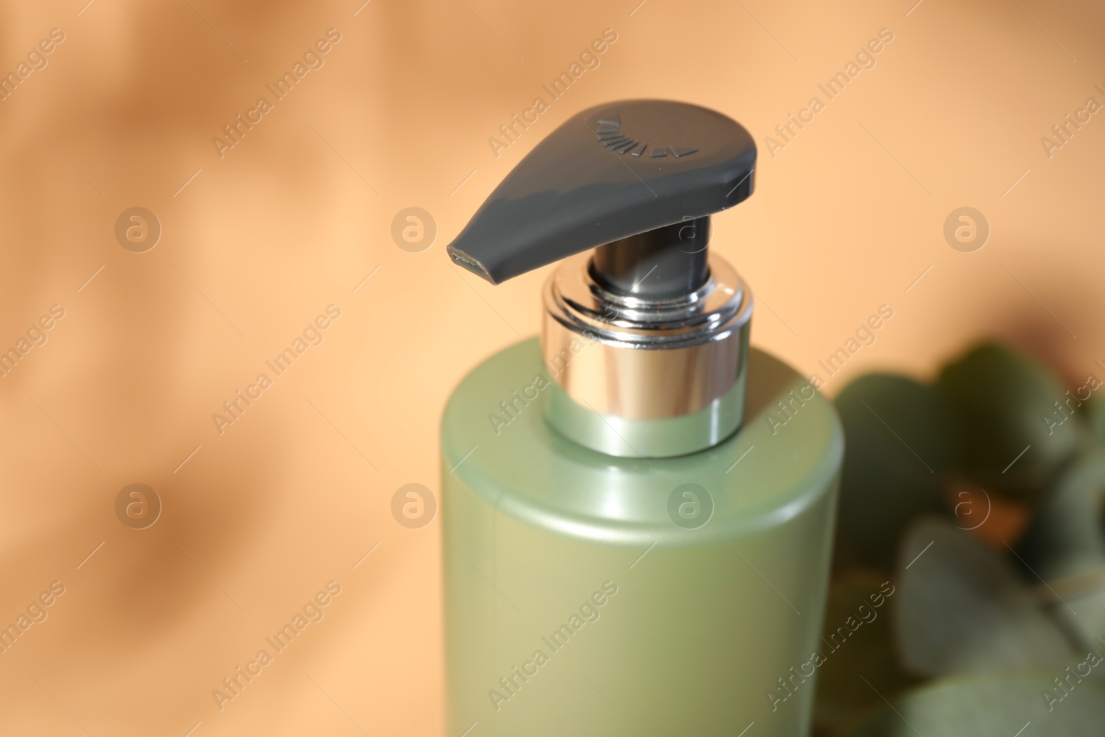 Photo of Shampoo in bottle on pale orange background, closeup