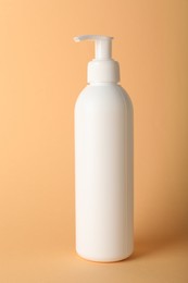 Photo of One shampoo in bottle on pale orange background