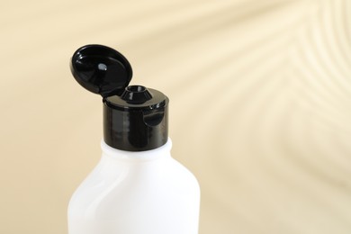 Photo of Shampoo in bottle on beige background, closeup. Space for text