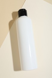 Photo of Shampoo in bottle on beige background, top view