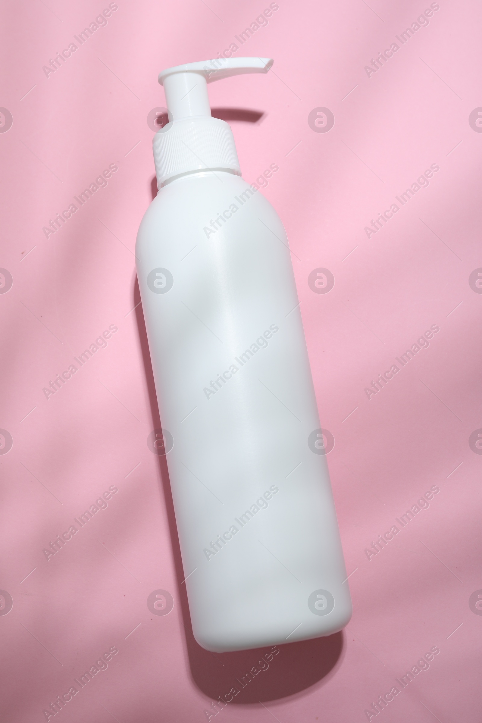 Photo of Shampoo in bottle on pink background, top view