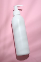 Photo of Shampoo in bottle on pink background, top view