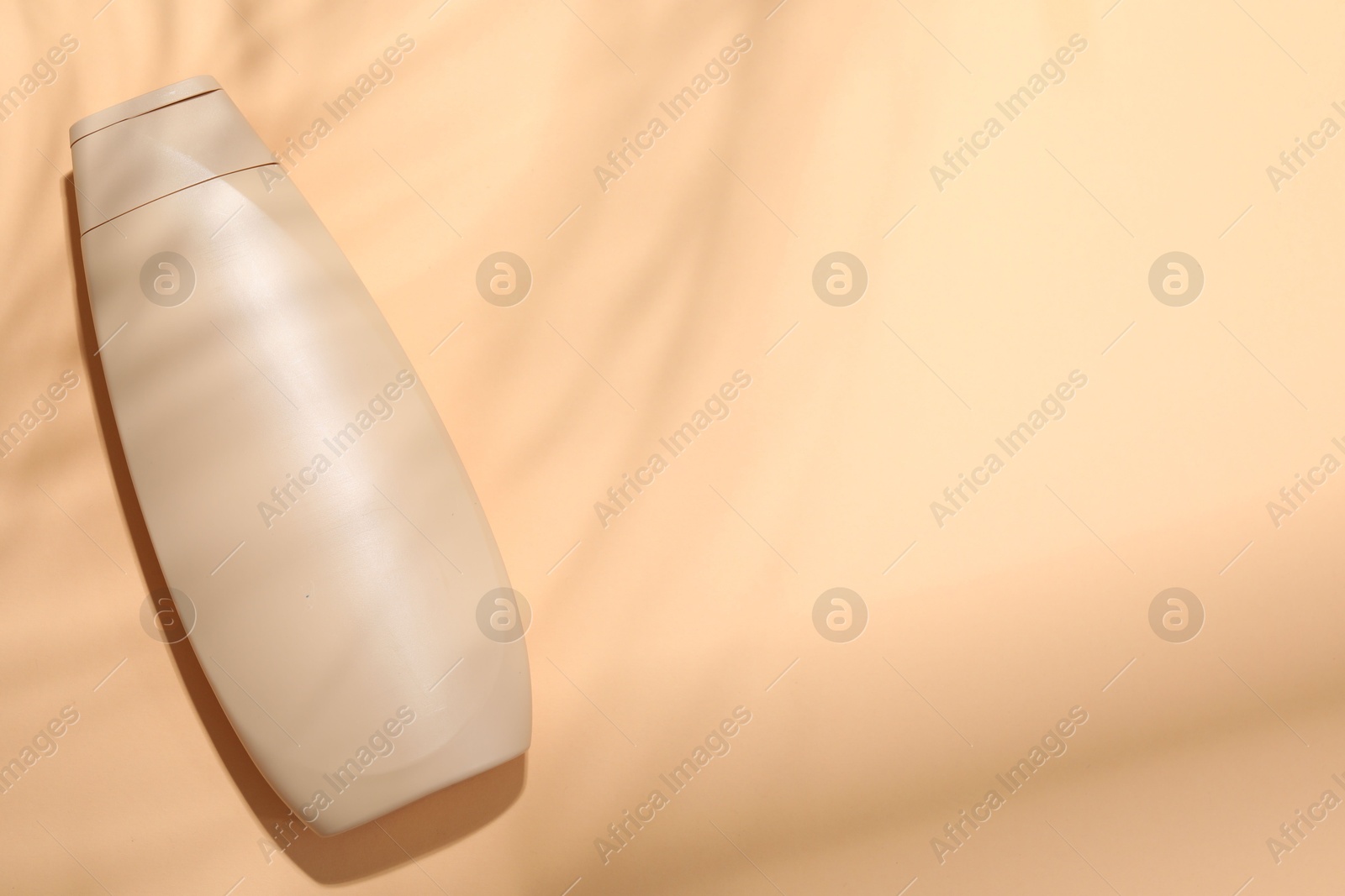 Photo of Shampoo in bottle on pale orange background, top view. Space for text