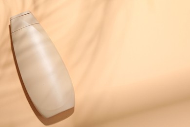 Shampoo in bottle on pale orange background, top view. Space for text