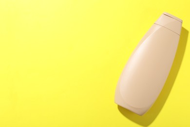 Photo of Shampoo in bottle on yellow background, top view. Space for text