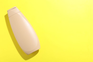 Photo of Shampoo in bottle on yellow background, top view. Space for text