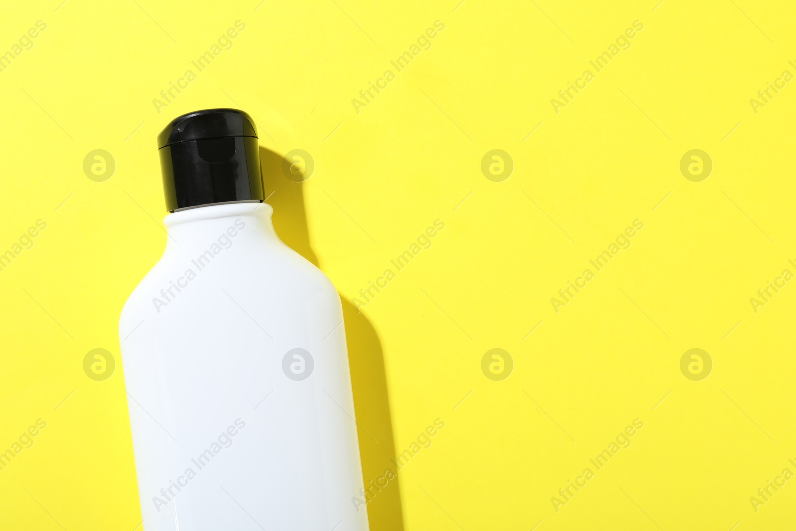 Photo of Shampoo in bottle on yellow background, top view. Space for text