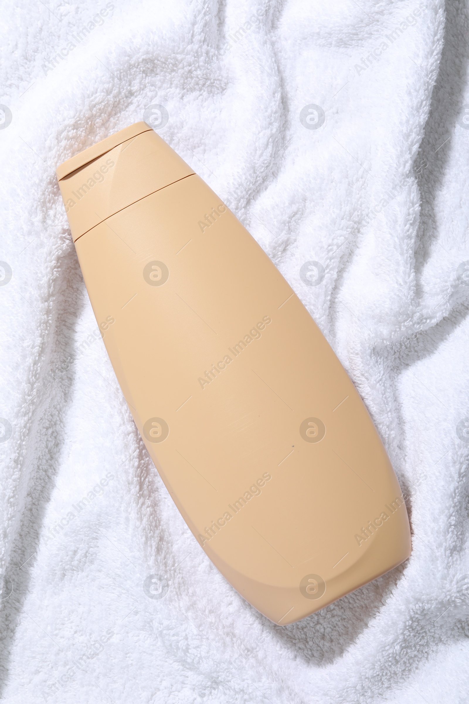 Photo of Shampoo in bottle on soft towel, top view