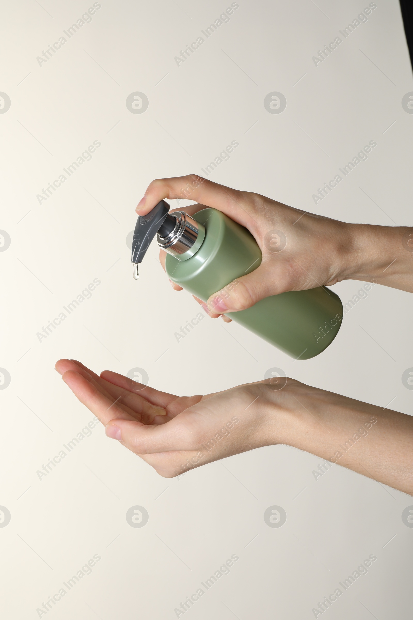 Photo of Woman pouring shampoo onto hand on beige background, closeup