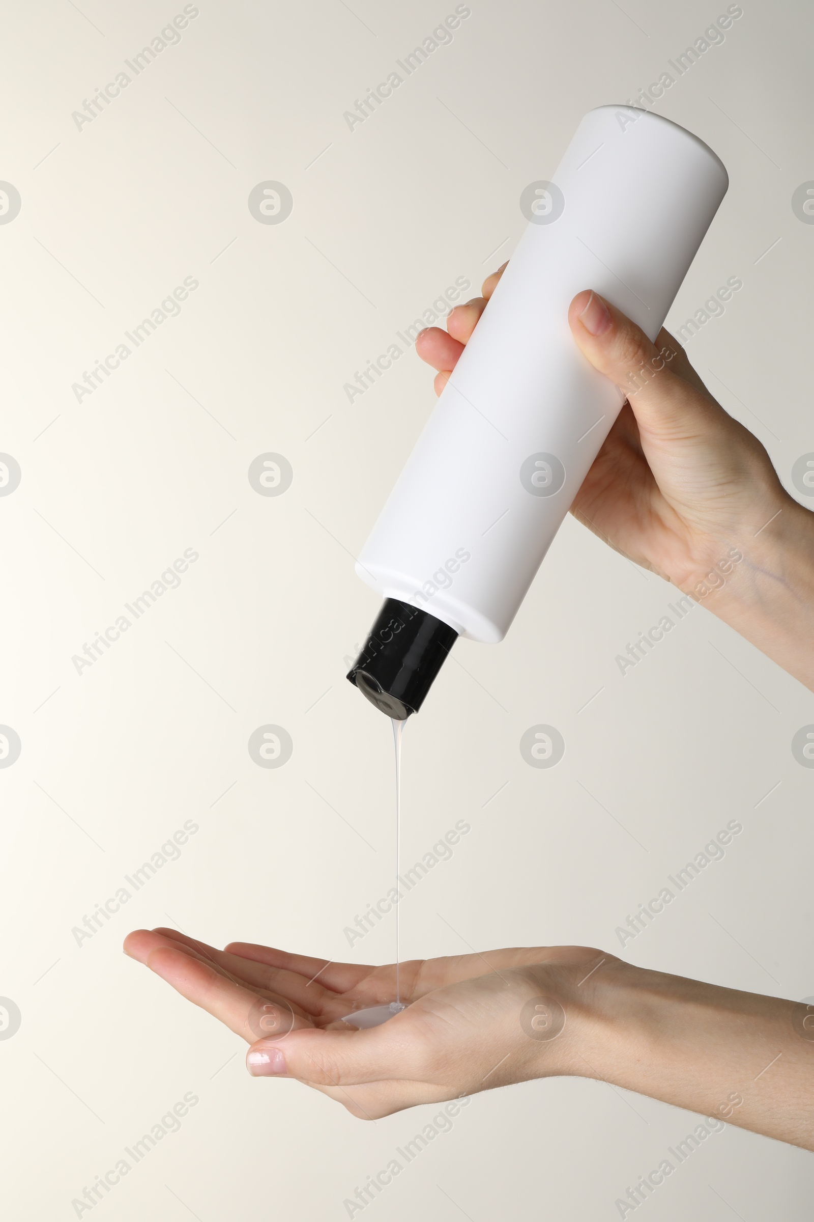 Photo of Woman pouring shampoo onto hand on beige background, closeup