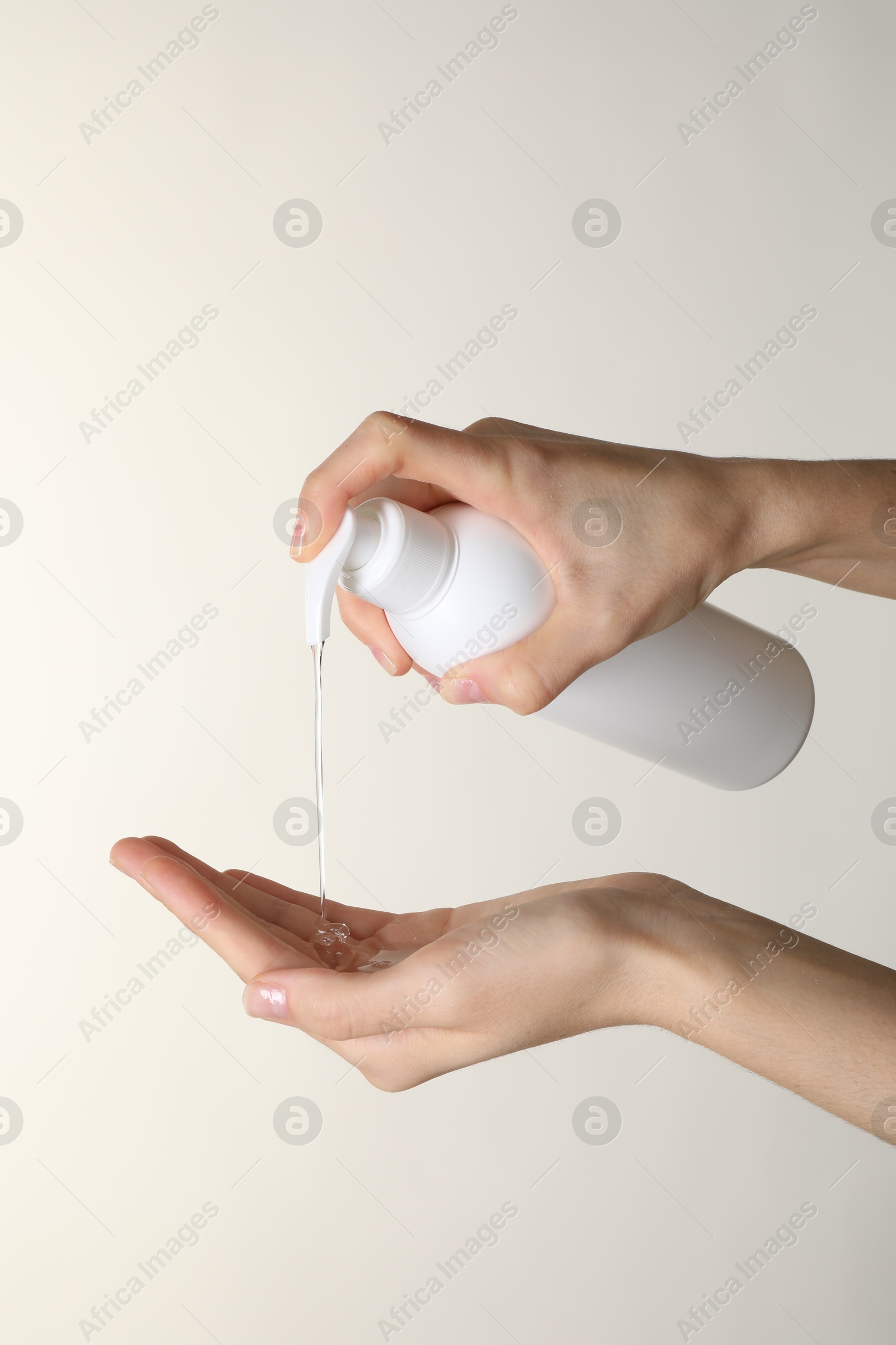 Photo of Woman pouring shampoo onto hand on beige background, closeup