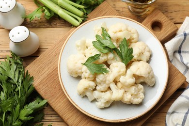 Photo of Tasty cauliflower with parsley on wooden table, flat lay