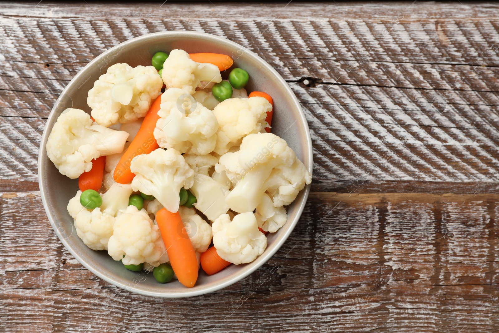 Photo of Tasty cauliflower with baby carrots and green peas on wooden table, top view. Space for text