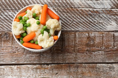 Photo of Tasty cauliflower with baby carrots and green peas on wooden table, top view. Space for text