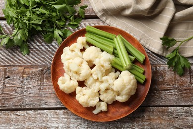 Photo of Tasty cauliflower with celery on wooden table, flat lay