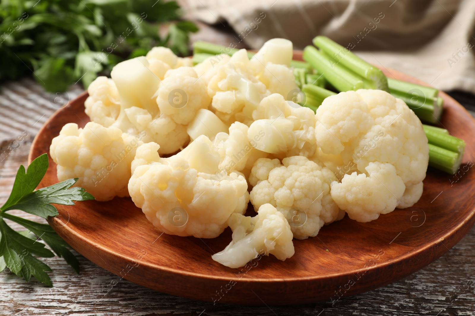 Photo of Tasty cauliflower with celery on wooden table, closeup