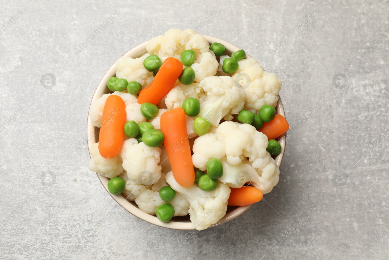 Photo of Tasty cauliflower with baby carrots and green peas on grey table, top view