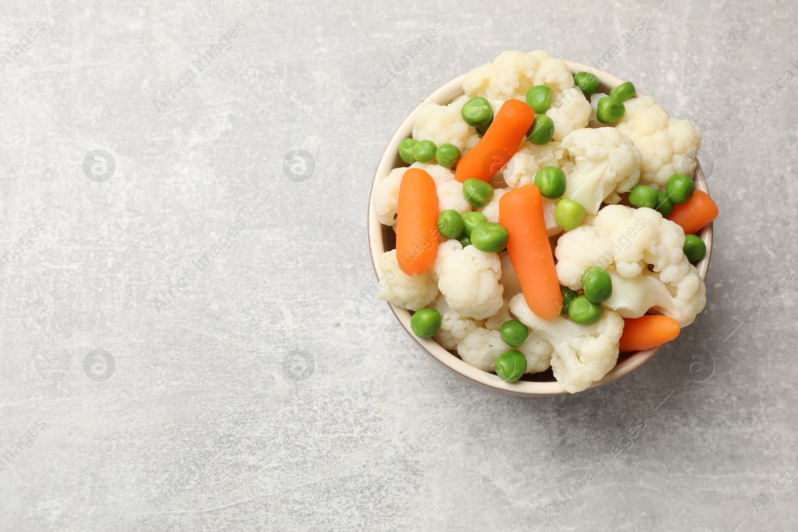 Photo of Tasty cauliflower with baby carrots and green peas on grey table, top view. Space for text