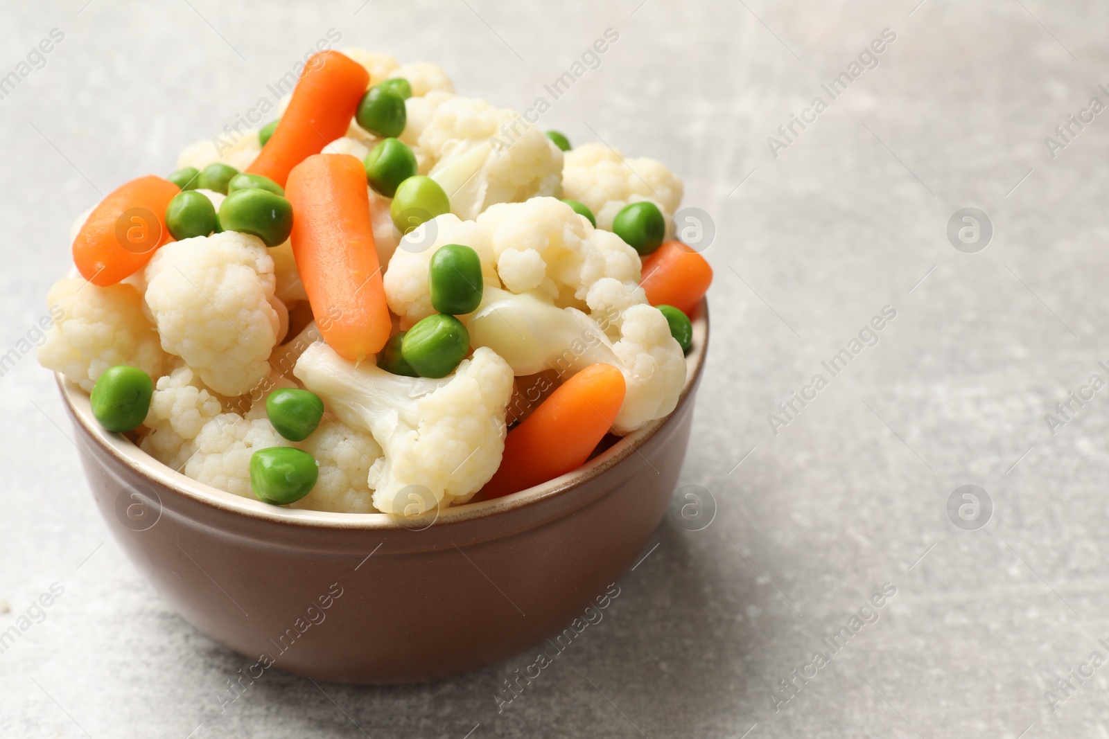 Photo of Tasty cauliflower with baby carrots and green peas on grey table, closeup. Space for text