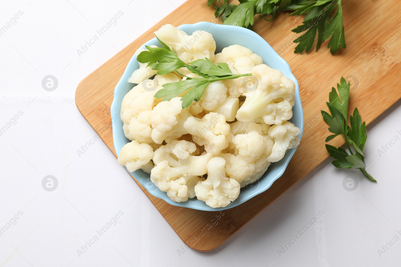 Photo of Tasty cauliflower with parsley on white tiled table, top view