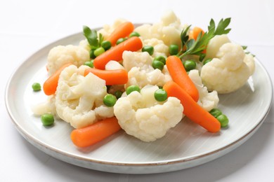 Photo of Tasty cauliflower with baby carrots and green peas on white table, closeup