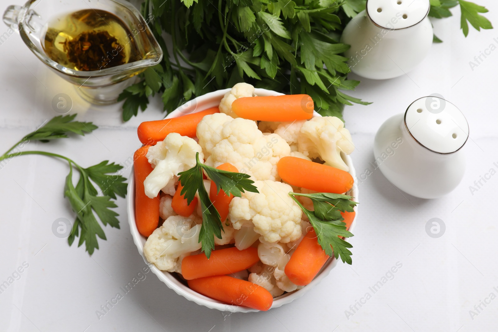 Photo of Tasty cauliflower with baby carrots and parsley on white tiled table, flat lay