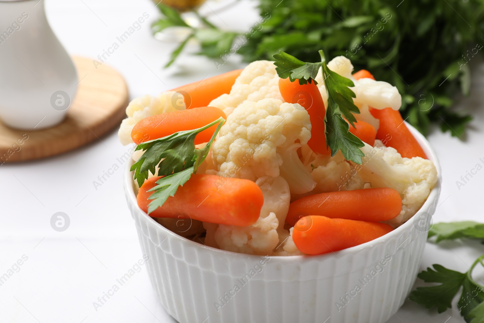 Photo of Tasty cauliflower with baby carrots and parsley on white table, closeup