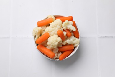 Photo of Tasty cauliflower with baby carrots on white tiled table, top view