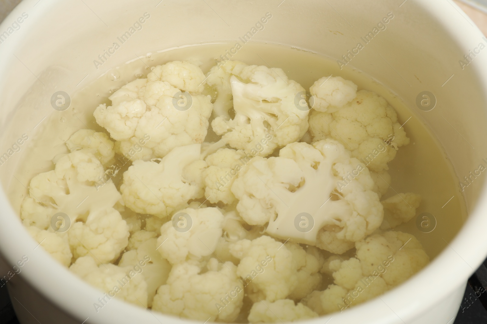 Photo of Cooking cauliflower. Florets in white pot with water, closeup