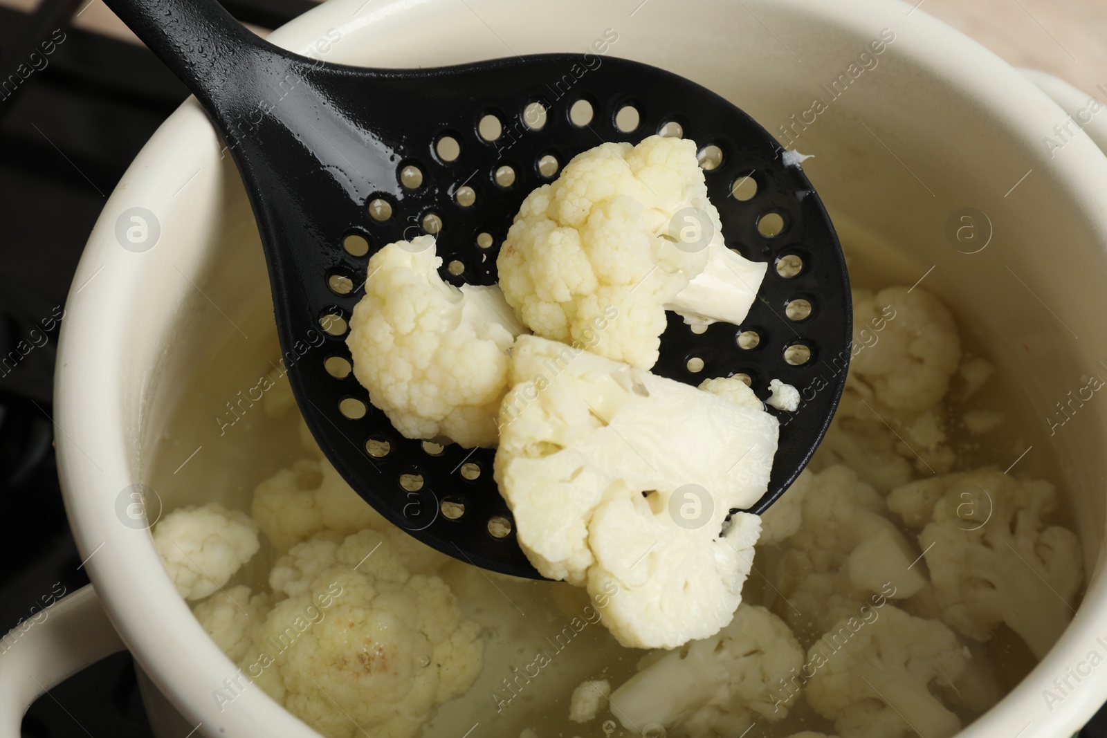 Photo of Taking boiled cauliflower from pot with skimmer, closeup