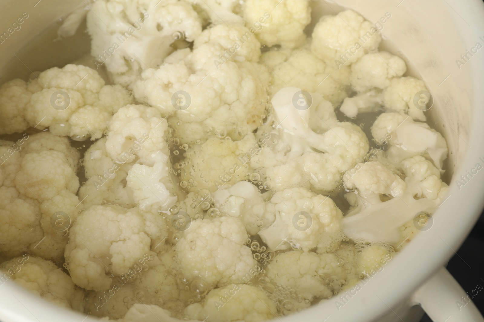 Photo of Cooking cauliflower. Florets in white pot with water, closeup