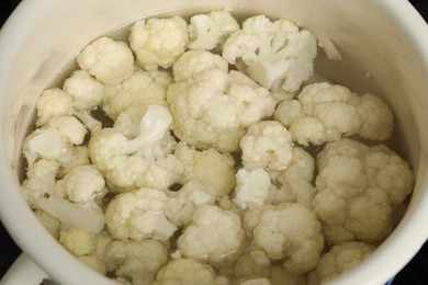 Photo of Cooking cauliflower. Florets in white pot with water, closeup